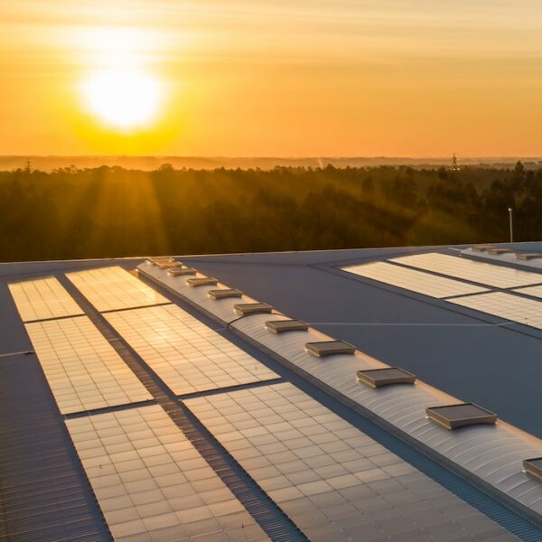 Photo d'un toit avec des panneaux solaires photovoltaïques d'occasion ou reconditionnés et d'un coucher de soleil en arrière plan.